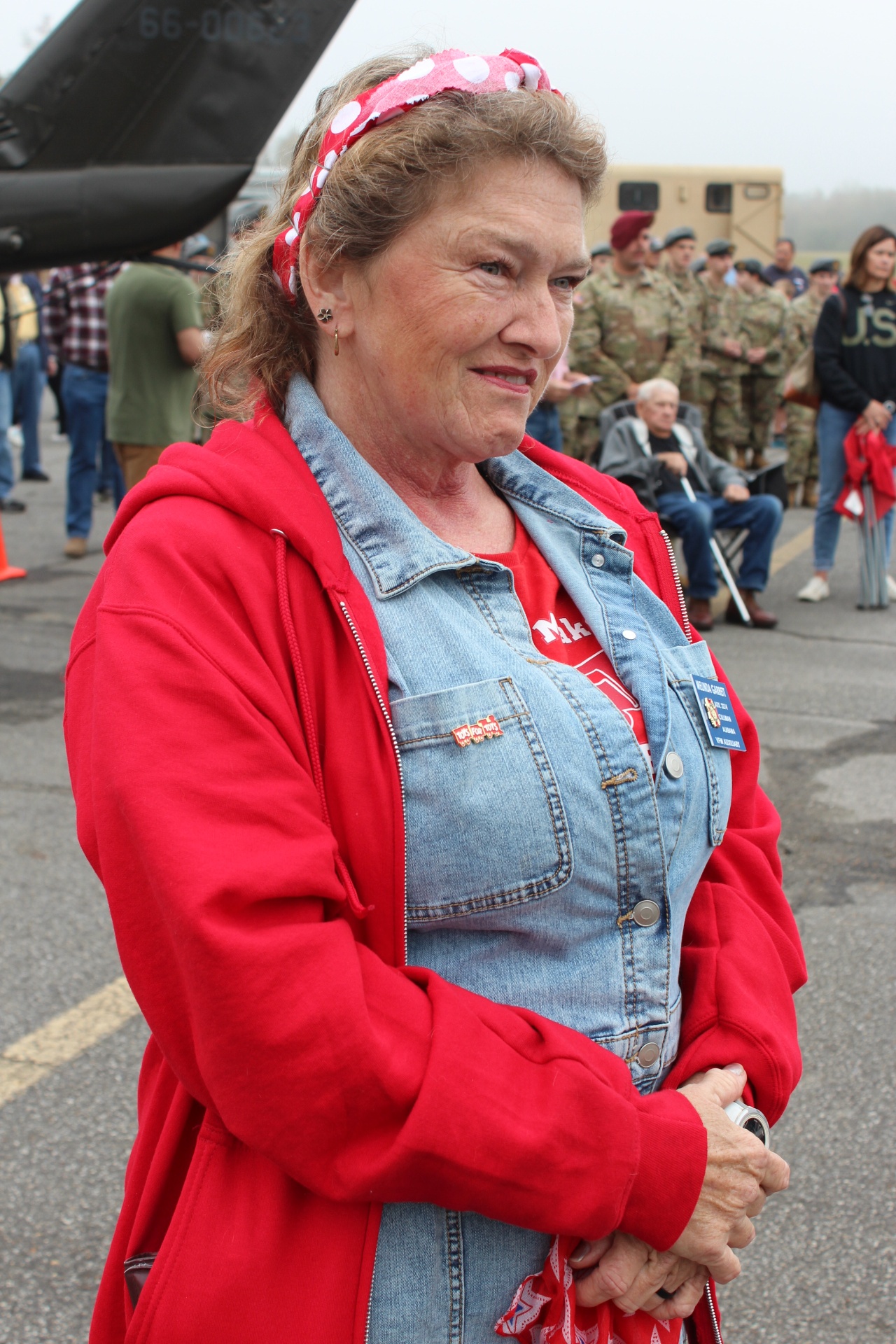 Rosie the Riveter volunteer in red-and-denim beside a Huey tail