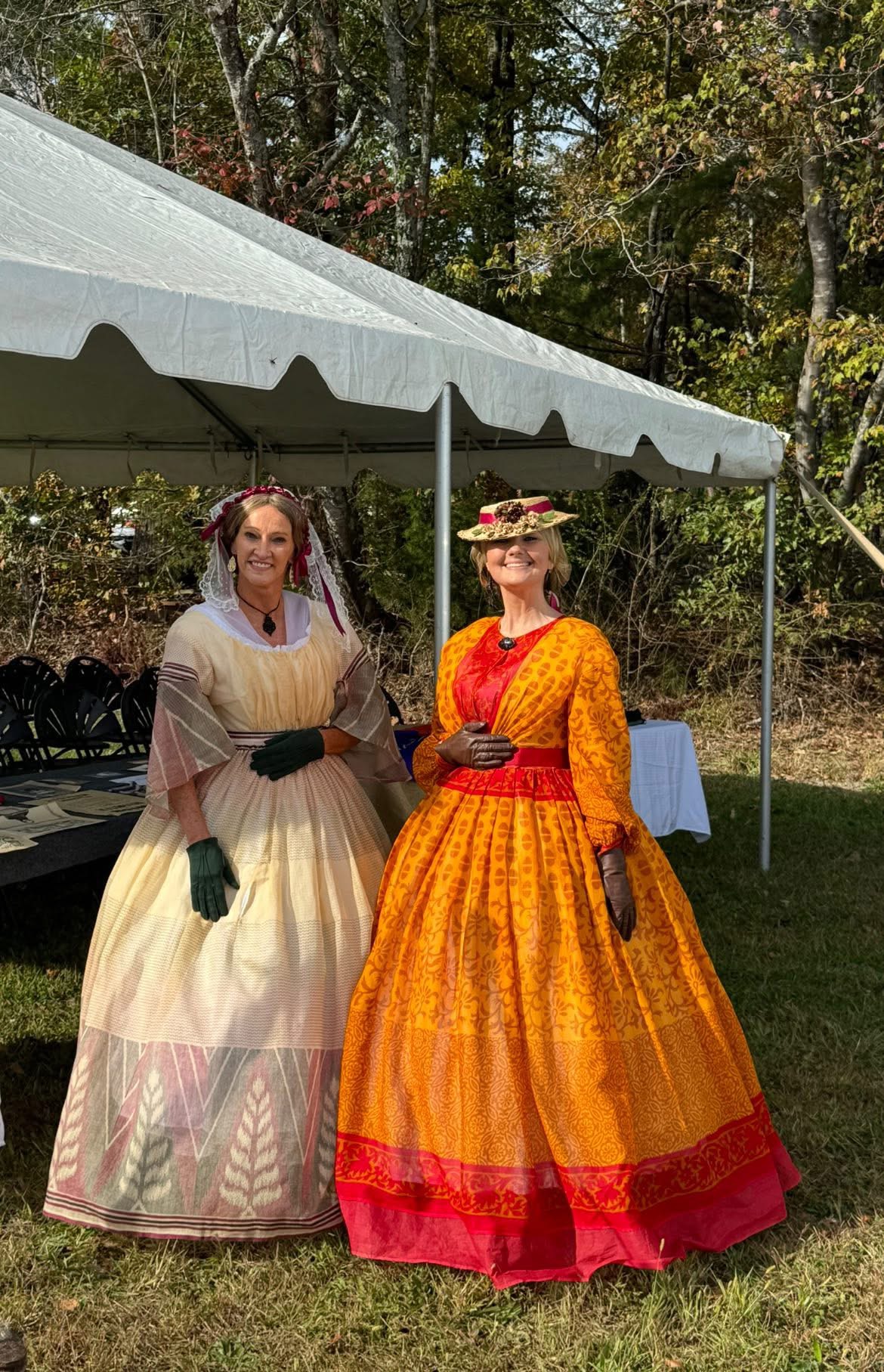 Two women in authentic 1860s civilian dresses under a tent