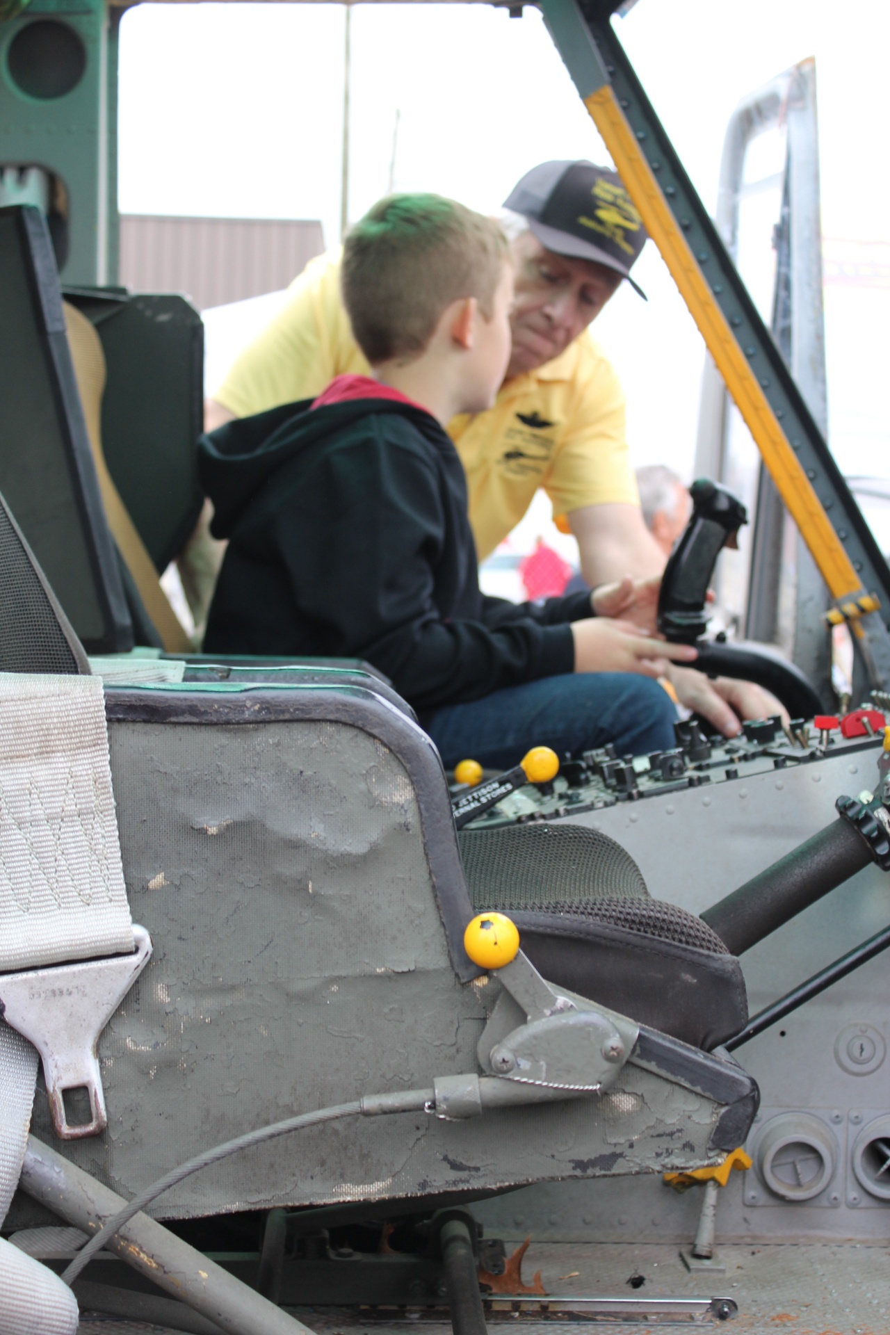 Volunteer pilot explains Huey cockpit controls to a young visitor
