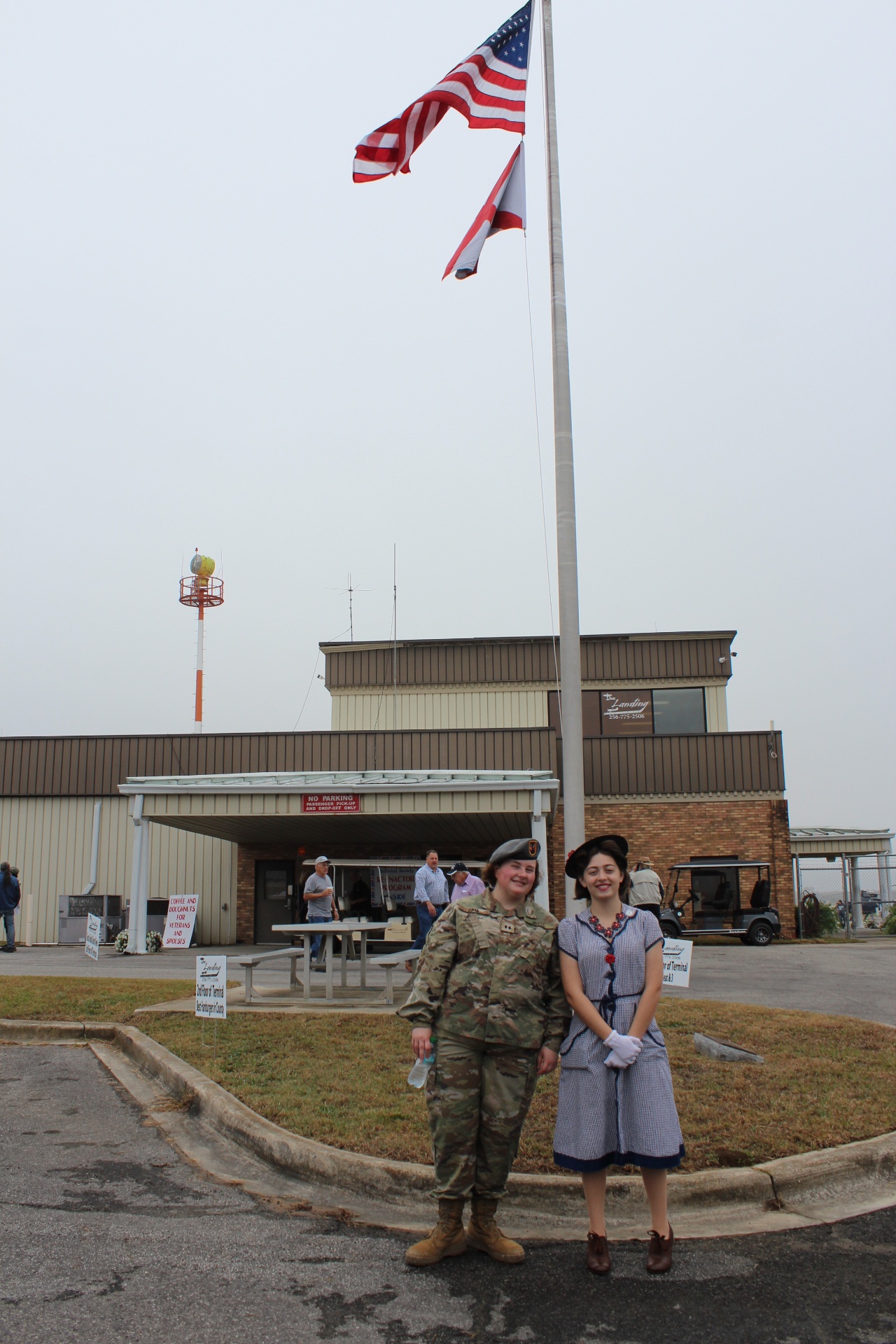 JROTC cadet and 1940s-era reenactor beneath the flag at Cullman Regional Airport