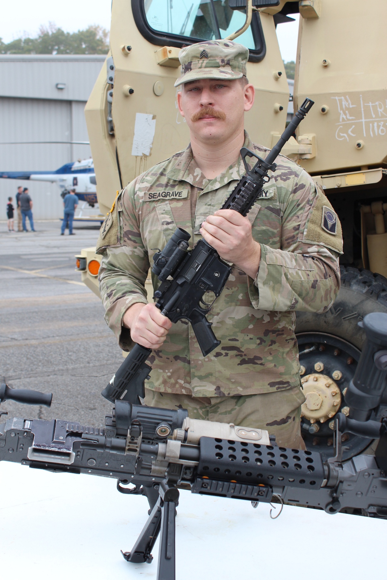 Alabama Guard NCO with rifle beside a National Guard MRAP
