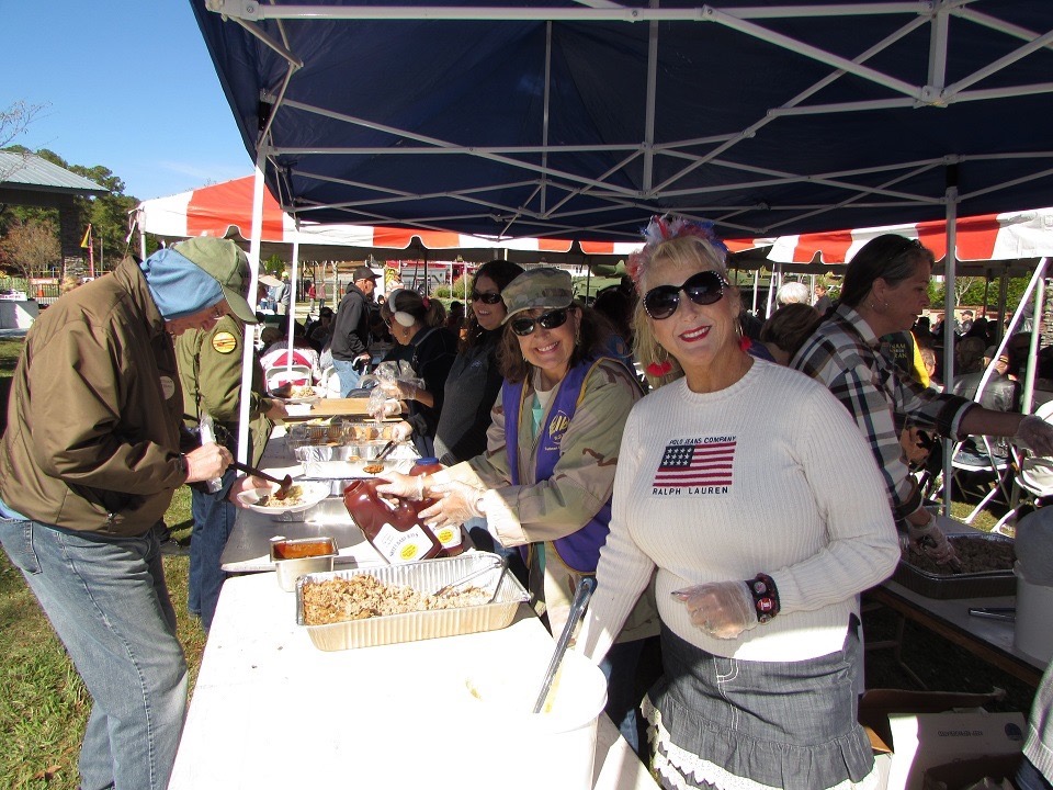 Volunteers serving hot lunch to veterans under the tent